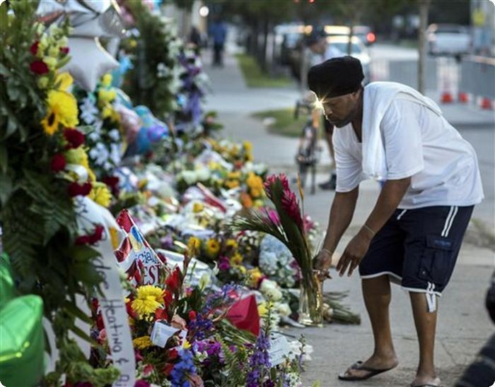 A man lays flowers on a memorial on the sidewalk outside the Emanuel AME Church, Saturday, June 20, 2015 in Charleston, S.C. People started visiting the site well before sunrise four days after a gunman shot and killed nine people during a Bible study session at the church Wednesday night. (AP Photo/Stephen B. Morton)