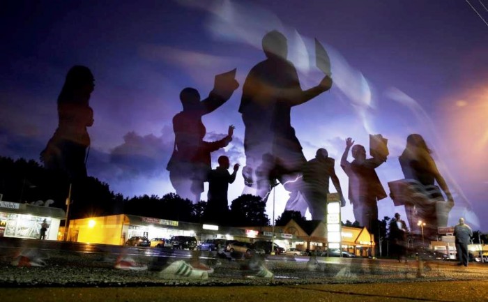 In this Aug. 20, 2014 file photo, protesters march in the street as lightning flashes in the distance in Ferguson, Mo. When a white Ferguson policeman fatally shot a young black man nearly a year ago, the St. Louis suburb erupted in violent protests and the nation took notice. Since then, legislators in almost every state have proposed changes to the way police interact with the public.(AP Photo/Jeff Roberson, File)