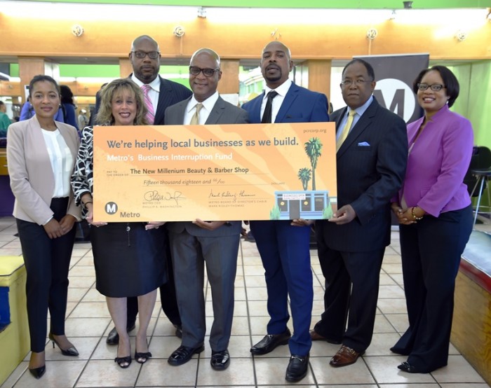 from (l-r) Shalonda Baldwin (Metro, Deputy Executive Officer), Andre Hardy (PCR, BIF Business Advisor), Angela Winston (PCR, BIF Program Manager), Mark Robertson (PCR, President/CEO), Desentrie Allen (owner), Metro Board Chair and LA County Supervisor Mark Ridley-Thomas, Stephanie Wiggins (Metro, Deputy CEO) present a $50,000 check to the owner of Millennium Barber Shop on Crenshaw Blvd. as part of Metro’s Business Interruption fund. ( Photo: Luis Inzunza/Metro)