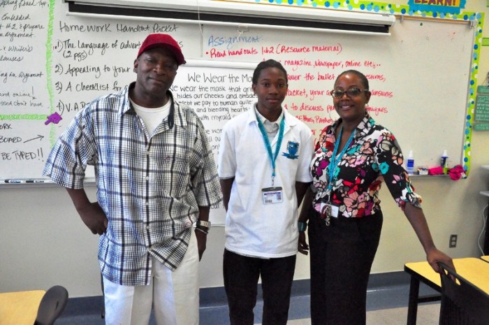 Caption: Parent Lee Trimble (left) visited his son Reginald's (center) English Language Arts class where he met with instructor Mona Walker (right) and participated in an analytical writing exercise.