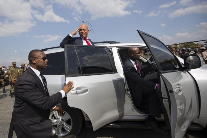 Haiti's outgoing President Michel Martelly delivers a goodbye salute to supporters before tucking into his vehicle outside the parliament building in Port-au-Prince, Haiti, Sunday, Feb. 7, 2016. Martelly made his farewell address to Parliament Sunday, leaving office with no leader yet chosen to fill the void left by his departure. Lawmakers are beginning a process to patch together a short-term interim government. (AP Photo/Dieu Nalio Chery)