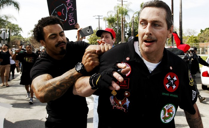 A counter protester tries to tear off the shirt of a Ku Klux Klansman after members of the KKK tried to start a "White Lives Matter" rally at Pearson Park in Anaheim on Saturday, Feb. 27, 2016. The event quickly escalated into violence and at least two people had to be treated at the scene for stab wounds. (Luis Sinco/Los Angeles Times via AP)