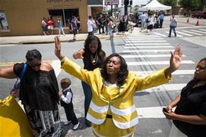 Annette Stubbs, a pastor at a local church, prays for victims a few blocks from a crime scene at the nightclub where a mass shooting took place the night before, along with members of her church, in Orlando, Fla., Sunday, June 12, 2016. A gunman opened fire inside the gay nightclub early Sunday, killing at least 50 people before dying in a gunfight with SWAT officers, police said. (Loren Elliott/Tampa Bay Times via AP)