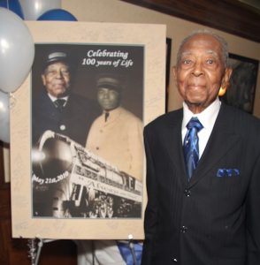 Lee Wesley Gibson at his 100th birthday party in 2010, standing by poster of him as a young Pullman Porter.