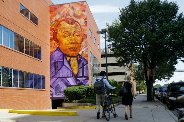 People walk past a Philadelphia Mural Arts Program piece depicting Bishop Richard Allen and the African Methodist Episcopal Church, in Philadelphia, Wednesday, July 6, 2016. The church marks its 200th anniversary in the city where it was founded by a former slave. (AP Photo/Matt Rourke)