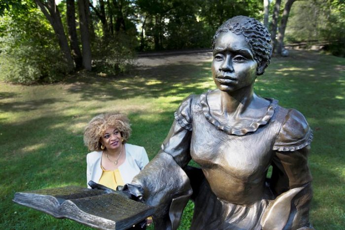 In this photo taken Thursday, Aug. 25, 2016, JerriAnne Boggis stands next to a statue of Harriet Wilson in Milford, N.H. Wilson, who was born in Milford, is considered the first female African-American to publish a novel on the North American continent. Boggis is part of a group of African-American and white scholars who are working on what they hope will be a statewide, black history trail that recognizes African-American contributions. (AP Photo/Jim Cole)