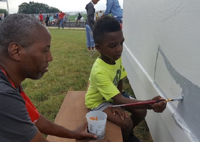 Cey Adams (left) watches Douglas Jackson, 7, stroke gray paint on a mural Sept. 24 during the grand opening celebration of the National Museum of African American History and Culture at the National Mall in Washington, D.C. (William J. Ford/The Washington Informer)