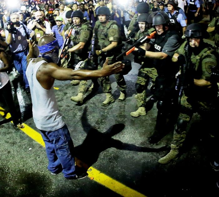 In this Aug. 9, 2014 file photo, police arrest a man as they disperse a protest in Ferguson, Mo. Police antagonized crowds gathered to protest the shooting of 18-year-old Michael Brown in Ferguson, violated free-speech rights and made it difficult to hold officers accountable, according to a U.S. Department of Justice report summary published Tuesday, June 30, 2015 by the St. Louis Post-Dispatch. (AP Photo/Charlie Riedel, File)