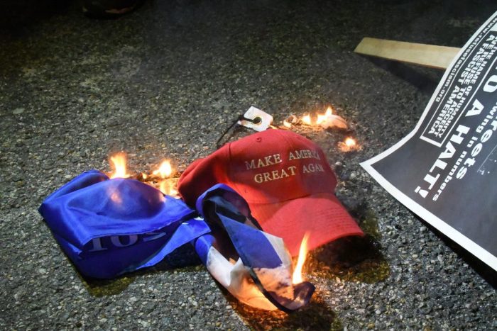 A “Make America Great Again” hat burns in the street in Washington, D.C. the night of the 2017 Inauguration. (Travis Riddick/The Washington Informer)