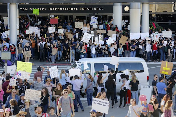 Demonstrators hold signs outside of Tom Bradley International Terminal as protests against President Donald Trump’s executive order banning travel from seven Muslim-majority countries continue at Los Angeles International Airport Sunday, Jan. 29, 2017. (AP Photo/Ryan Kang)